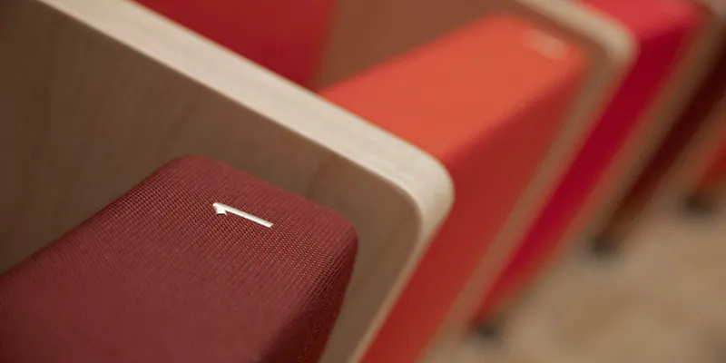 kantoor-nowystyl-collegestoelen-2000x1000px2 Een close-up van een houten collegestoel van Nowy Styl met rode zitting