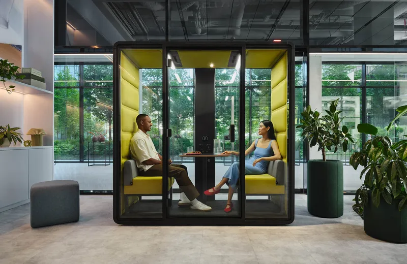 kantoorinrichting-vergadercabines-mikomax-access-L 1000x650px7 Een sfeerfoto van 2 mensen in overleg in een Mikomax hushFree XM cabine met geel interieur